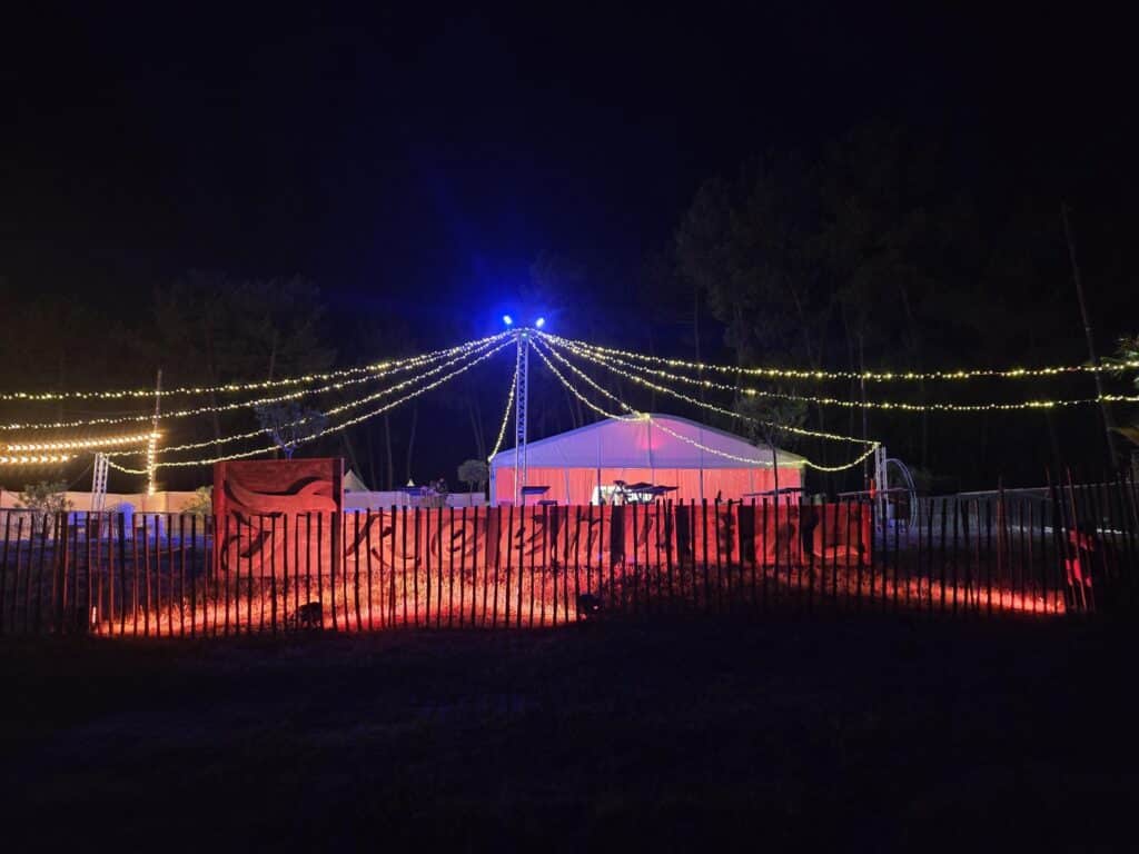 Structure de mât et guirlandes lumineuses éclairant un chapiteau évènementiel de nuit - Elec Expo