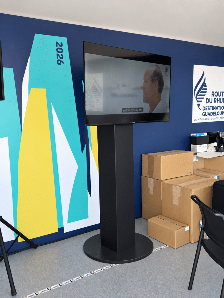 Écran de présentation installé sur un stand événementiel avec support au sol