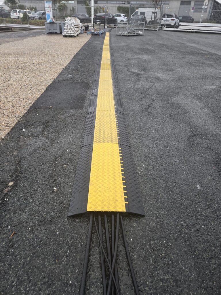 Passage de câbles électriques protégé par une rampe de protection jaune et noire