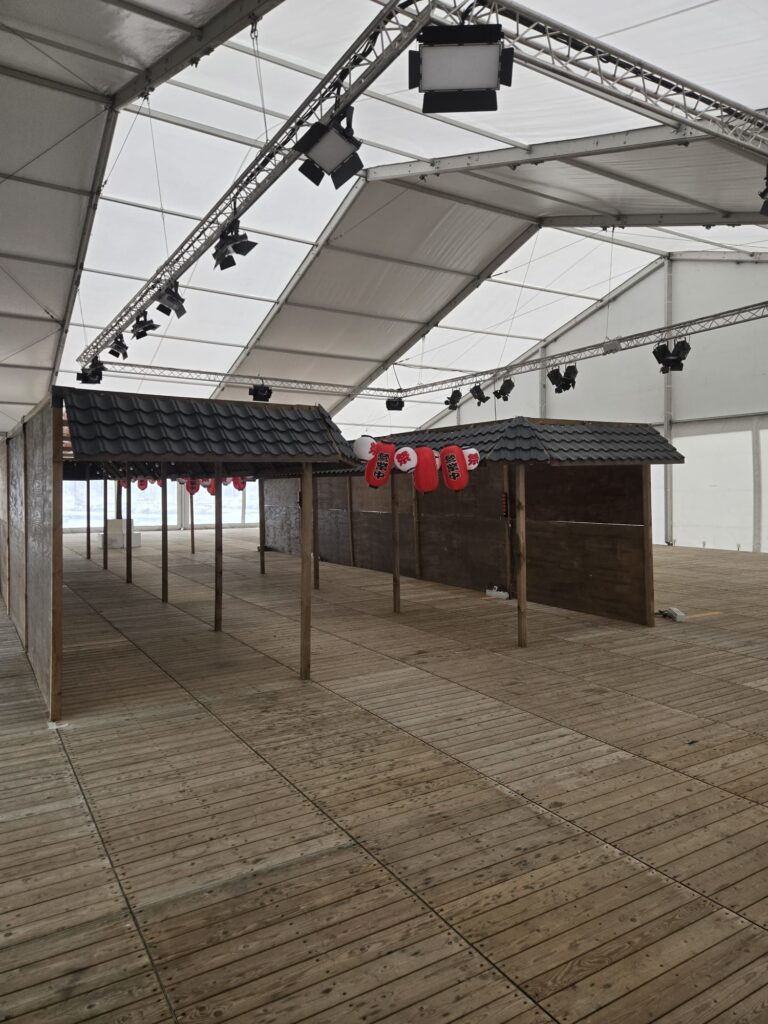 Éclairage événementiel installé sous une tente avec structures et projecteurs